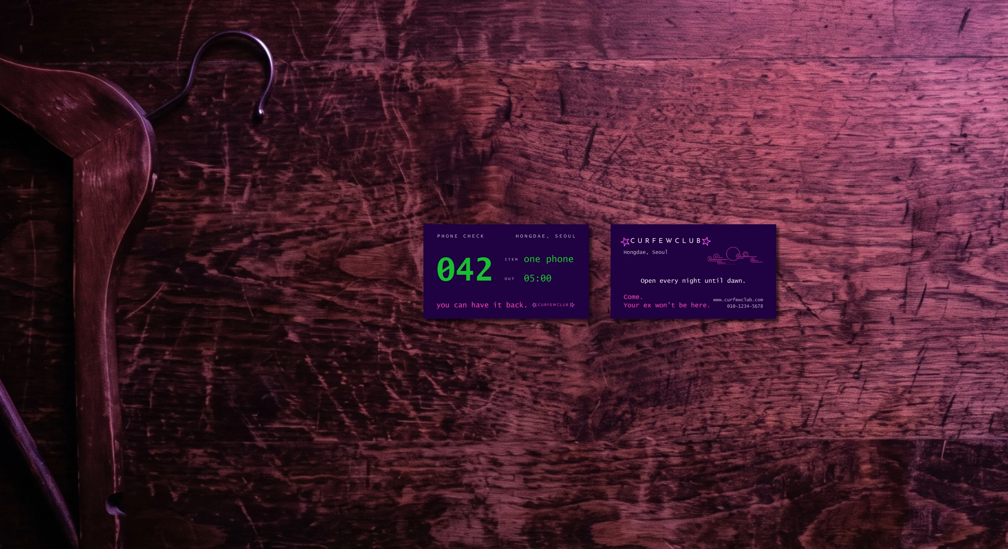 The dark, scratched wooden top of a cloakroom counter, seen from above and lit in magenta. On the left, lying on the counter, a wooden coat hanger. In the middle, side by side, the two sides of the same card. The front: the number «042» large, and beside it the lines «ITEM one phone» and «OUT 05:00». The back: the CURFEWCLUB mark, «Hongdae, Seoul», «Open every night until dawn.» and, in magenta, «Come. Your ex won't be here.»
